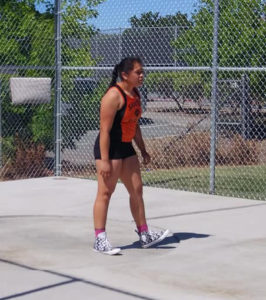 Athlete prepares for pole vault on a track with others watching.
