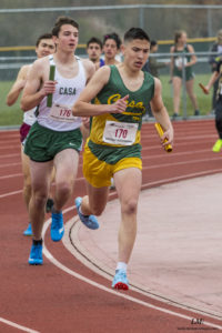 Athlete prepares for pole vault on a track with others watching.