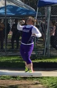 Athlete prepares for pole vault on a track with others watching.