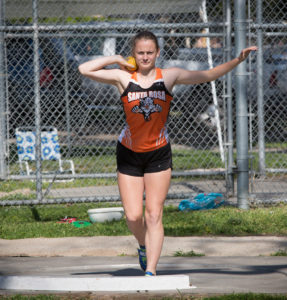 Athlete prepares for pole vault on a track with others watching.