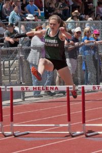 Athlete prepares for pole vault on a track with others watching.