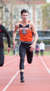 Athlete prepares for pole vault on a track with others watching.