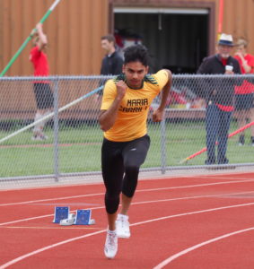 Athlete prepares for pole vault on a track with others watching.
