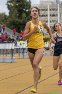 Athlete prepares for pole vault on a track with others watching.