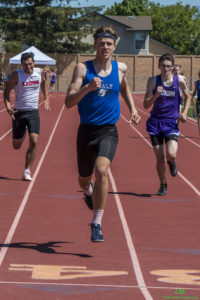 Athlete prepares for pole vault on a track with others watching.