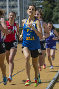 Athlete prepares for pole vault on a track with others watching.