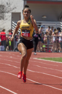 Athlete prepares for pole vault on a track with others watching.