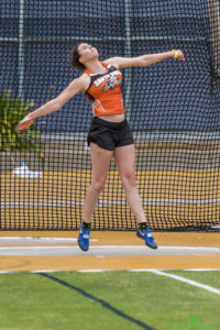 Athlete prepares for pole vault on a track with others watching.