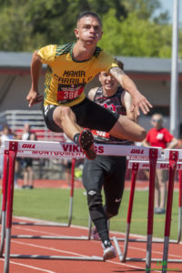 Athlete prepares for pole vault on a track with others watching.