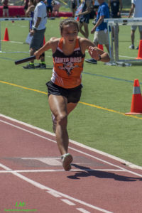 Athlete prepares for pole vault on a track with others watching.