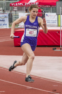 Athlete prepares for pole vault on a track with others watching.