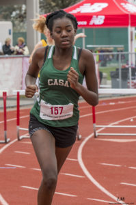 Athlete prepares for pole vault on a track with others watching.