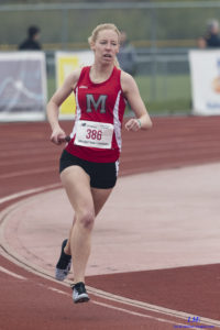 Athlete prepares for pole vault on a track with others watching.