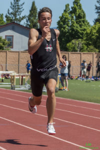 Athlete prepares for pole vault on a track with others watching.