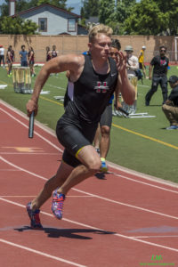 Athlete prepares for pole vault on a track with others watching.