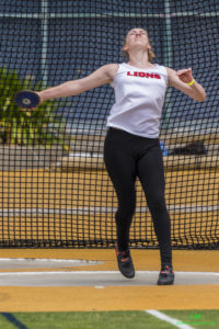 Athlete prepares for pole vault on a track with others watching.