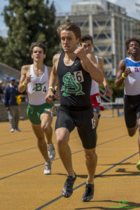 Athlete prepares for pole vault on a track with others watching.