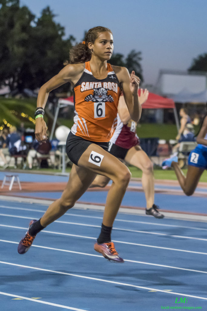 Athlete prepares for pole vault on a track with others watching.