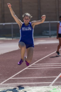 Athlete prepares for pole vault on a track with others watching.