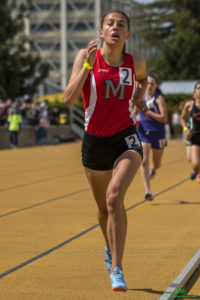 Athlete prepares for pole vault on a track with others watching.