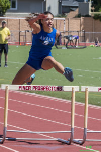 Athlete prepares for pole vault on a track with others watching.