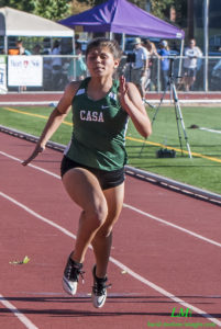 Athlete prepares for pole vault on a track with others watching.