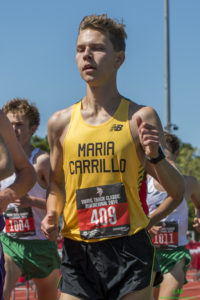 Athlete prepares for pole vault on a track with others watching.