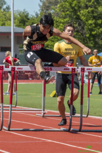 Athlete prepares for pole vault on a track with others watching.