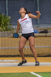 Athlete prepares for pole vault on a track with others watching.