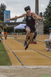Athlete prepares for pole vault on a track with others watching.