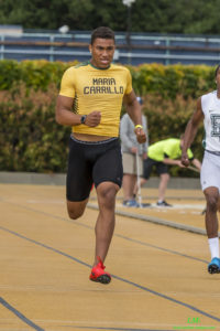 Athlete prepares for pole vault on a track with others watching.