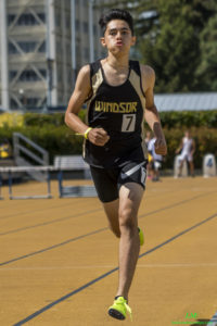 Athlete prepares for pole vault on a track with others watching.