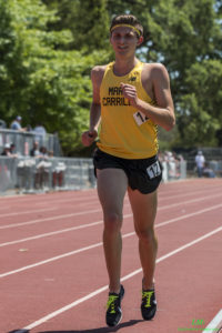 Athlete prepares for pole vault on a track with others watching.