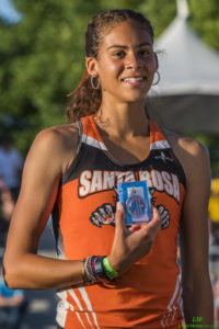Athlete prepares for pole vault on a track with others watching.