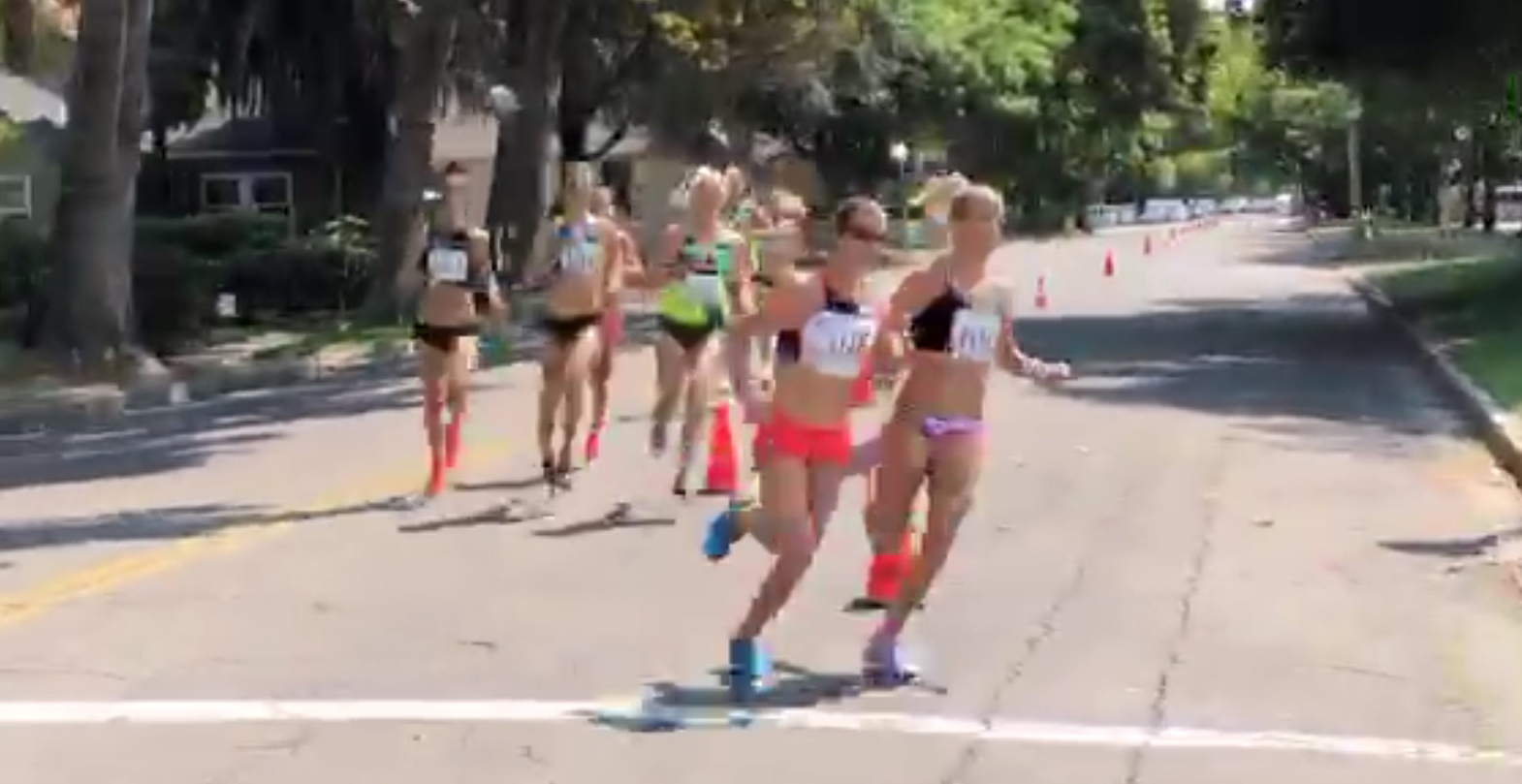 Athlete prepares for pole vault on a track with others watching.