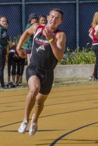 Athlete prepares for pole vault on a track with others watching.