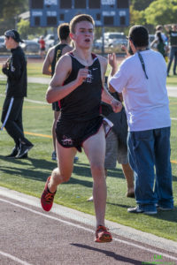 Athlete prepares for pole vault on a track with others watching.
