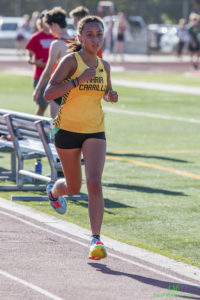 Athlete prepares for pole vault on a track with others watching.
