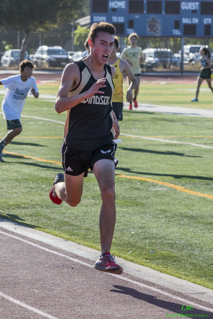 Athlete prepares for pole vault on a track with others watching.