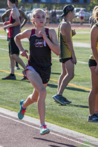 Athlete prepares for pole vault on a track with others watching.