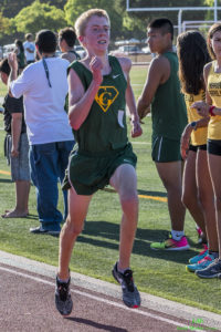 Athlete prepares for pole vault on a track with others watching.
