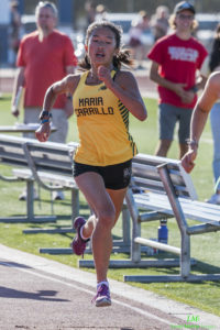Athlete prepares for pole vault on a track with others watching.
