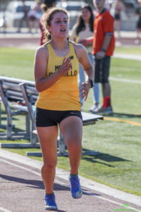Athlete prepares for pole vault on a track with others watching.