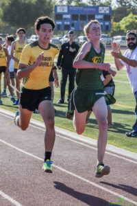 Athlete prepares for pole vault on a track with others watching.