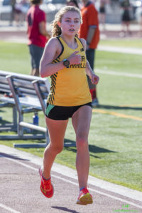 Athlete prepares for pole vault on a track with others watching.