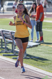 Athlete prepares for pole vault on a track with others watching.
