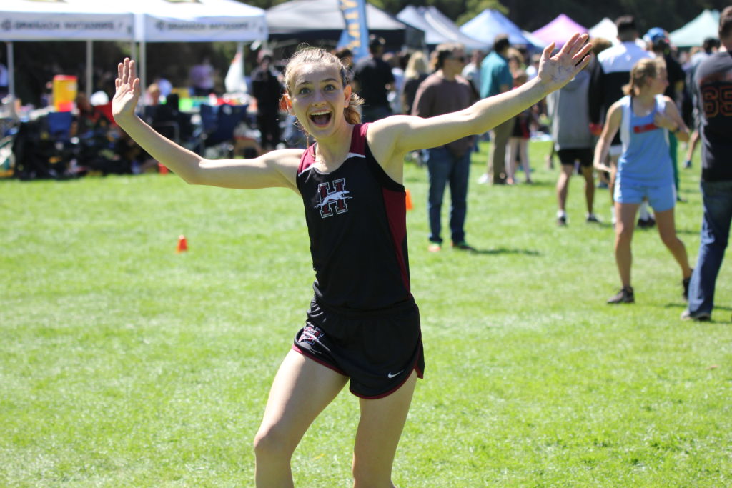 Athlete prepares for pole vault on a track with others watching.