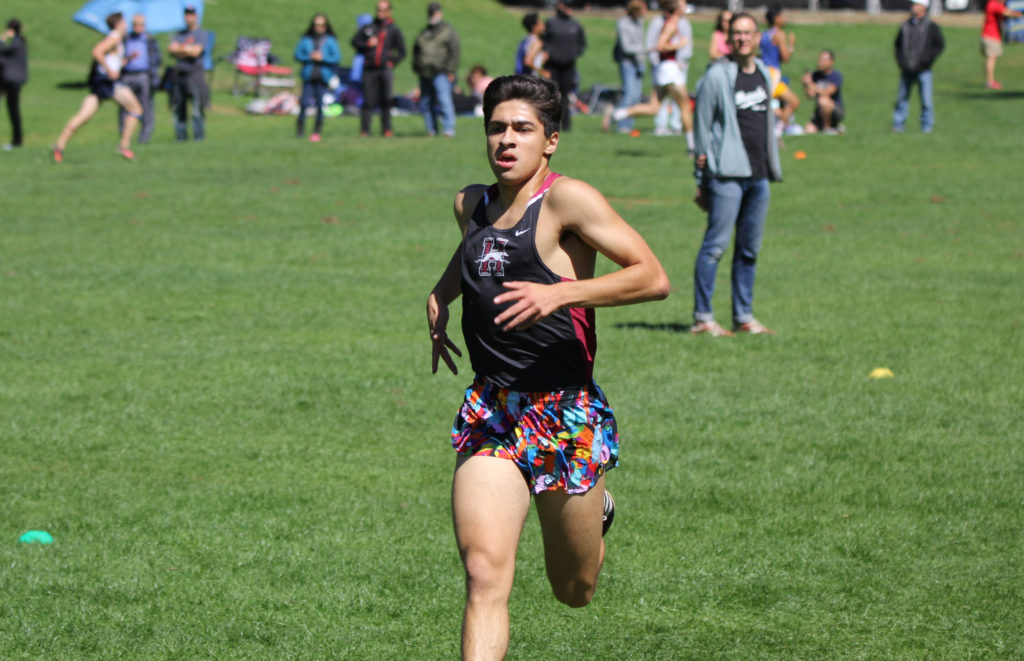 Athlete prepares for pole vault on a track with others watching.