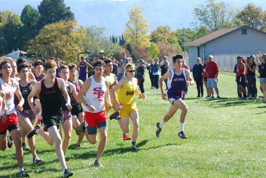 Athlete prepares for pole vault on a track with others watching.