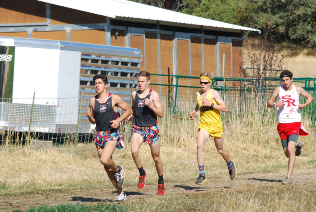 Athlete prepares for pole vault on a track with others watching.